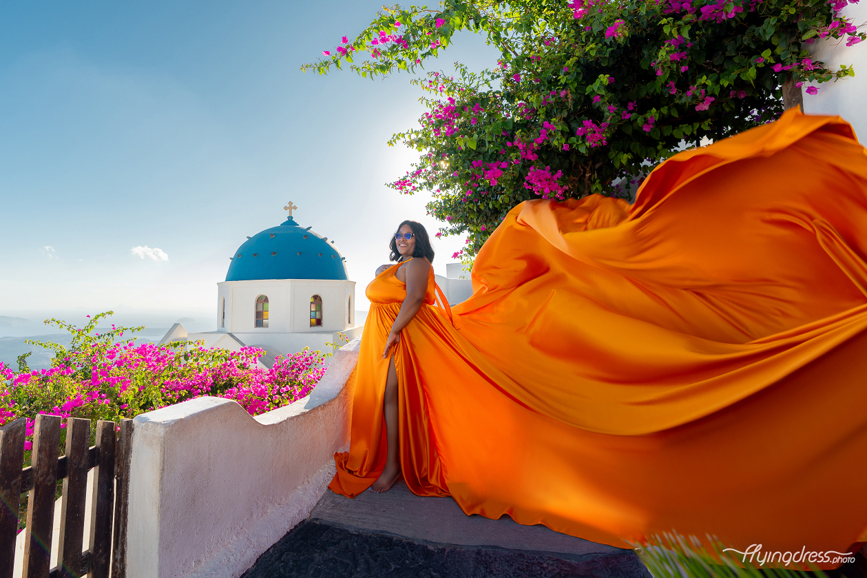 A glowing tangerine train takes flight against Santorini's blue dome, pink bougainvillea, and sun-drenched sky.